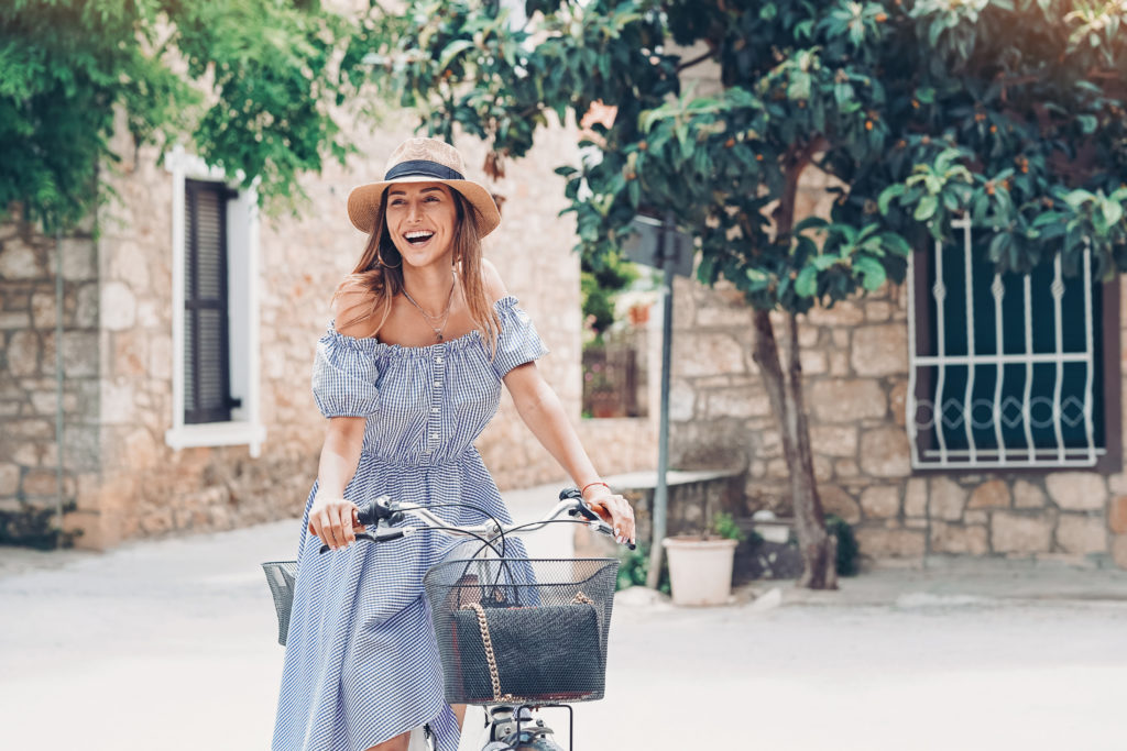 kobieta w sukience z opadającymi ramionami na rowerze