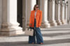 kobieta w stylizacji z szerokimi spodniami, pomarańczową marynarką i szpilkami