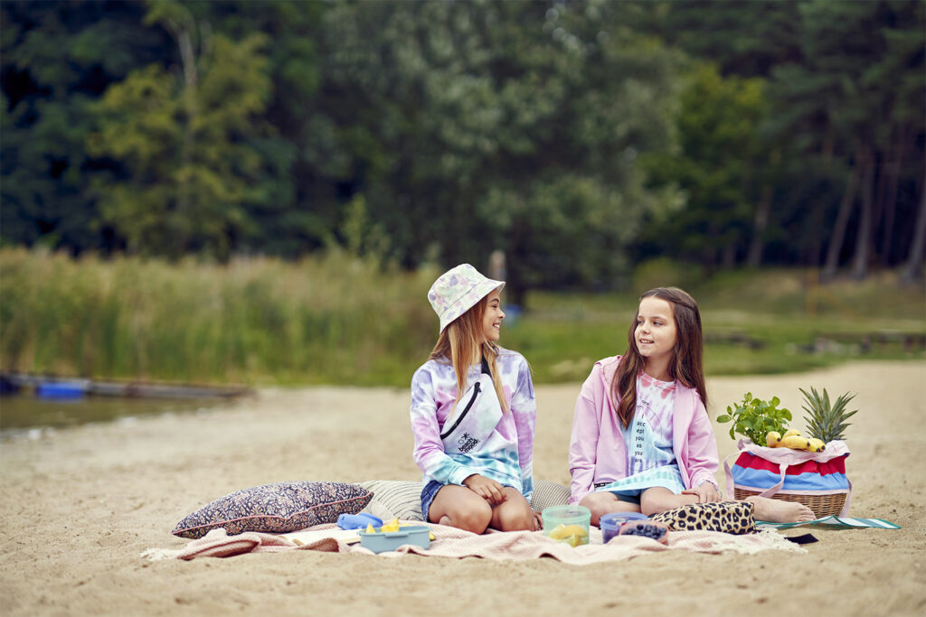 Dziewczynki na plaży w kolorowych bluzach dziecięcych