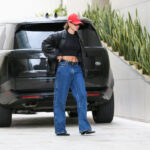 Hailey Bieber w szerokich jeansach, kurtce skórzanej i czapce z daszkiem