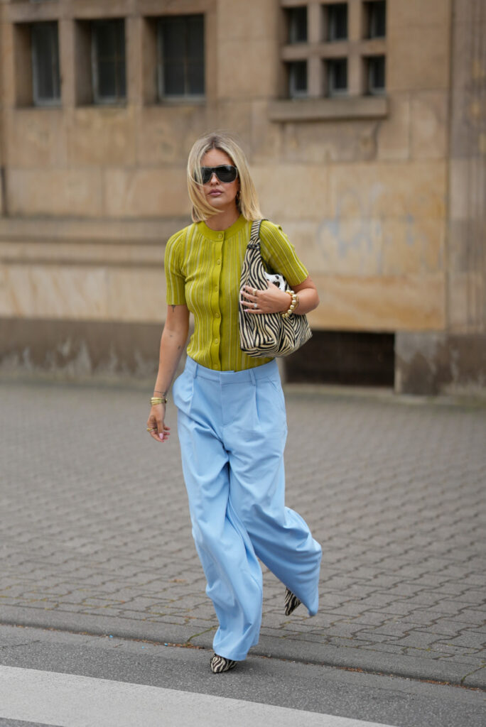 Błękitne spodnie wide leg w street style na wiosnę i lato 2026 zestawione z limonkowym topem i torebką w zebrę